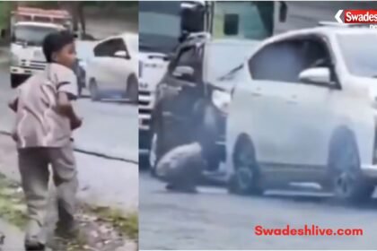 A young boy stops a rolling car by placing a stone under its tyre, preventing a possible accident.