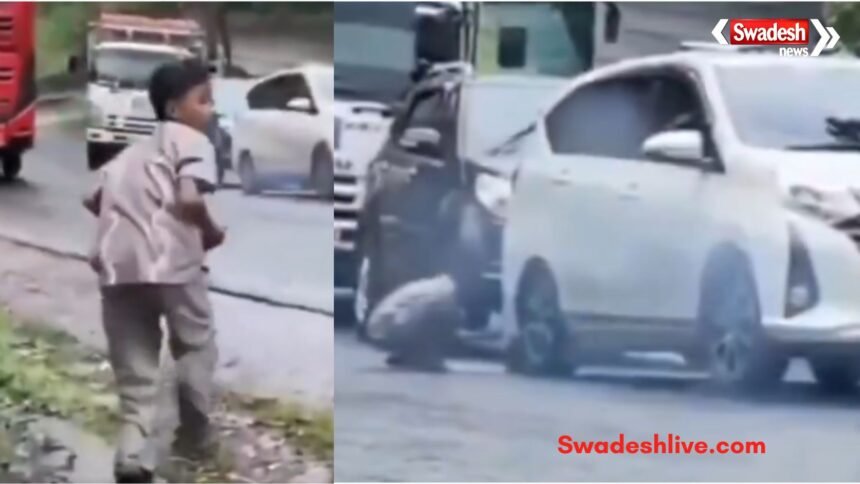 A young boy stops a rolling car by placing a stone under its tyre, preventing a possible accident.